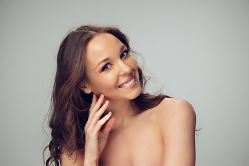 Image showing Close up of beautiful young woman with long healthy curly hair and bright make up isolated on grey studio backgroud, smiling with white teeth