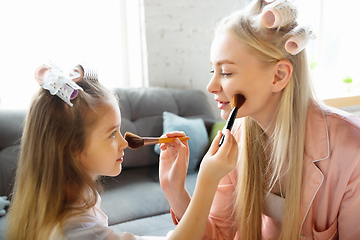 Image showing Mother and daughter, sisters have quite, beauty and fun day together at home. Comfort and togetherness. Do a make up, using cosmetics, masks, moisturizers, brushes and lipsticks