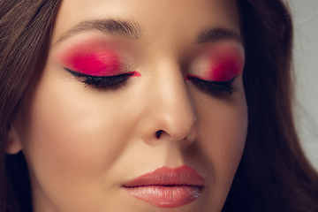 Image showing Close up of beautiful young woman with long healthy curly hair and bright make up isolated on grey studio backgroud