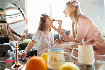 Image showing Mother and daughter, sisters have quite, beauty and fun day together at home. Comfort and togetherness. Do a make up, using cosmetics, masks, moisturizers, brushes and lipsticks