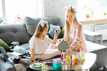 Image showing Mother and daughter, sisters have quite, beauty and fun day together at home. Comfort and togetherness. Do a make up, using cosmetics, masks, moisturizers, brushes and lipsticks