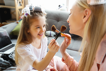 Image showing Mother and daughter, sisters have quite, beauty and fun day together at home. Comfort and togetherness. Do a make up, using cosmetics, masks, moisturizers, brushes and lipsticks