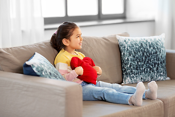 Image showing happy little girl with heart shaped pillow at home