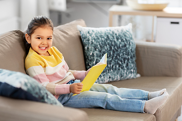 Image showing happy smiling little girl reading book at home