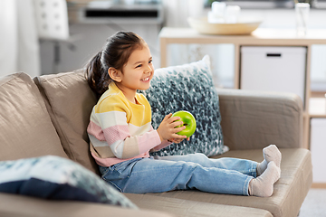 Image showing happy little girl with apple sitting on sofa