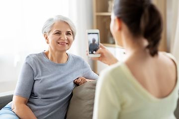 Image showing adult daughter photographing senior mother at home