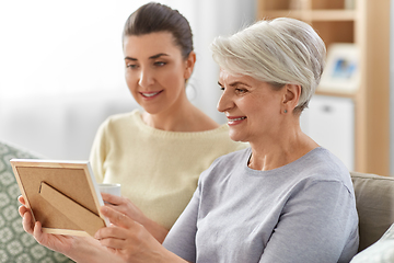 Image showing adult daughter and old mother with photo at home