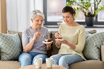 Image showing old mother and adult daughter eating cake at home