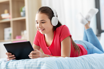 Image showing girl in headphones listening to music on tablet pc