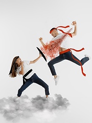 Image showing Colorful drawing in cartoon style collaged with portrait of young caucasian couple fighting like ninjas on cloud in flight