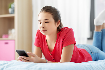 Image showing sad teenage girl texting on smartphone at home