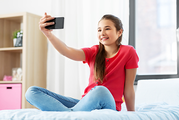 Image showing happy girl with smartphone taking selfie at home