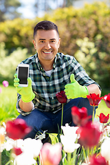 Image showing man with phone showing thumbs up at flowers garden