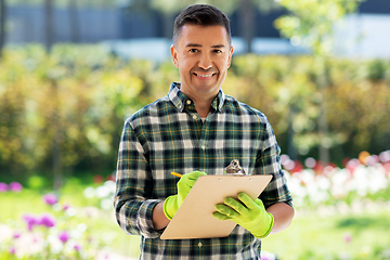 Image showing man with clipboard and flowers at summer garden