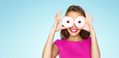 Image showing happy woman or teen girl looking through donuts