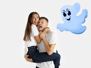 Image showing Colorful drawing in cartoon style collaged with portrait of young caucasian couple. Man holding his woman, they scared of funny ghost