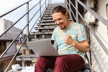 Image showing Young man, businessman working, studying outdoors, looking on computer screen, monitor. Copyspace.