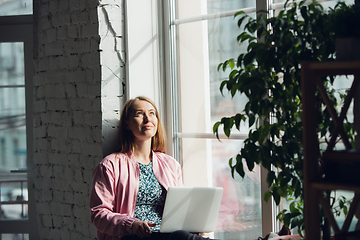 Image showing Young woman, businesswoman working or studying at home with laptop near window. Attented, concentrated. Copyspace.