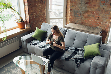 Image showing Young woman, businesswoman working or studying at home, looking on computer screen, monitor. Attented, concentrated. Copyspace. Top view.