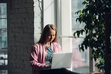 Image showing Young woman, businesswoman working or studying at home with laptop near window. Attented, concentrated. Copyspace.