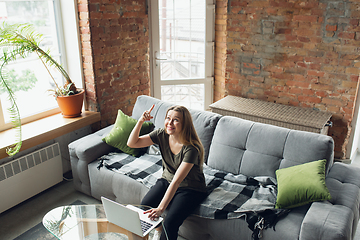 Image showing Young woman, businesswoman working or studying at home, looking on computer screen, monitor. Attented, concentrated. Copyspace. Top view.