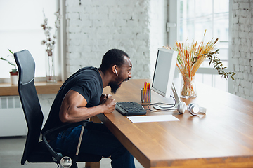 Image showing Young man, businessman working in office, looking on blank black computer screen, monitor. Copyspace.