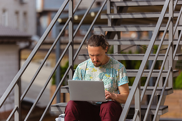 Image showing Young man, businessman working, studying outdoors, looking on computer screen, monitor. Copyspace.