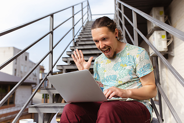 Image showing Young man, businessman working, studying outdoors, looking on computer screen, monitor. Copyspace.