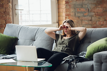 Image showing Young woman, businesswoman working or studying at home with laptop sitting on sofa. Attented, concentrated. Copyspace.