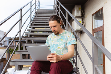 Image showing Young man, businessman working, studying outdoors, looking on computer screen, monitor. Copyspace.