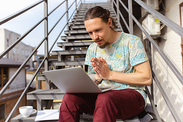 Image showing Young man, businessman working, studying outdoors, looking on computer screen, monitor. Copyspace.