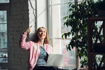 Image showing Young woman, businesswoman working or studying at home with laptop near window. Attented, concentrated. Copyspace.