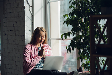 Image showing Young woman, businesswoman working or studying at home with laptop near window. Attented, concentrated. Copyspace.