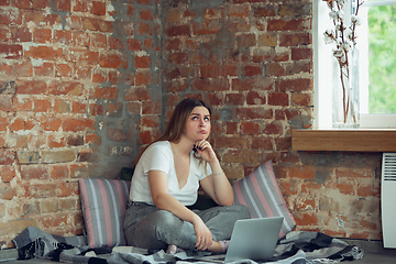 Image showing Young woman, businesswoman working or studying at home with laptop near window. Attented, concentrated. Copyspace.