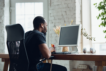 Image showing Young man, businessman working in office, looking on blank black computer screen, monitor. Copyspace.