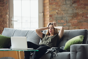 Image showing Young woman, businesswoman working or studying at home with laptop sitting on sofa. Attented, concentrated. Copyspace.