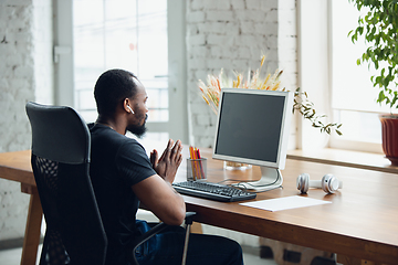 Image showing Young man, businessman working in office, looking on blank black computer screen, monitor. Copyspace.