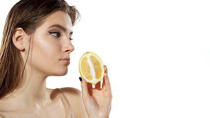 Image showing Vitamins. Beautiful young woman with lemon slice over white background. Cosmetics and makeup, natural and eco treatment, skin care. Flyer with copyspace.