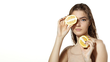 Image showing Vitamins. Beautiful young woman with lemon slice over white background. Cosmetics and makeup, natural and eco treatment, skin care. Flyer with copyspace.
