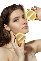 Image showing Organic. Beautiful young woman with lemon slice over white background. Cosmetics and makeup, natural and eco treatment, skin care.