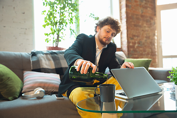 Image showing Young man in pajama and jacket working on a computer, laptop. Remote office during coronavirus, fun and comfortable work in underpants