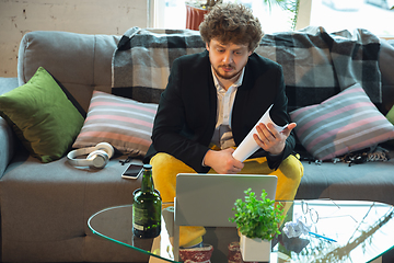 Image showing Young man in pajama and jacket working on a computer, laptop. Remote office during coronavirus, fun and comfortable work in underpants