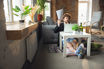 Image showing Young man without pants but in jacket working on a computer, laptop. Remote office during coronavirus, fun and comfortable work in underpants