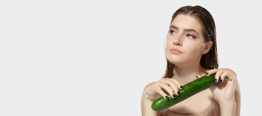 Image showing Youth secrets. Close up of beautiful young woman with cucumber over white background. Cosmetics and makeup, natural and eco treatment, skin care. Flyer with copyspace.