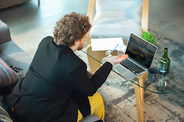 Image showing Young man in pajama and jacket working on a computer, laptop. Remote office during coronavirus, fun and comfortable work in underpants