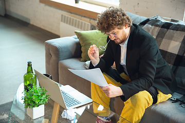 Image showing Young man in pajama and jacket working on a computer, laptop. Remote office during coronavirus, fun and comfortable work in underpants