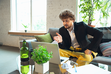 Image showing Young man in pajama and jacket working on a computer, laptop. Remote office during coronavirus, fun and comfortable work in underpants