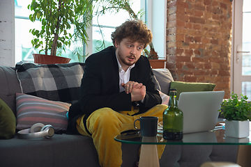 Image showing Young man in pajama and jacket working on a computer, laptop. Remote office during coronavirus, fun and comfortable work in underpants