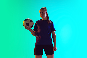 Image showing Female soccer, football player holding ball, posing confident isolated on gradient background. Copyspace.