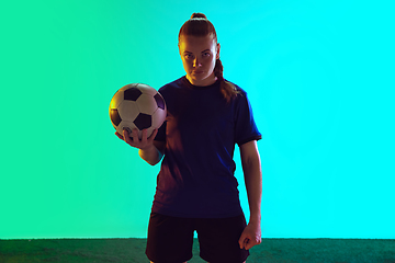 Image showing Female soccer, football player holding ball, posing confident isolated on gradient background. Copyspace.